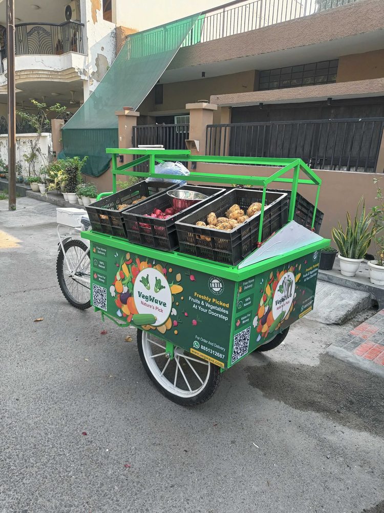 The VegWave cart parked in a lane, loaded with crates of vegetables